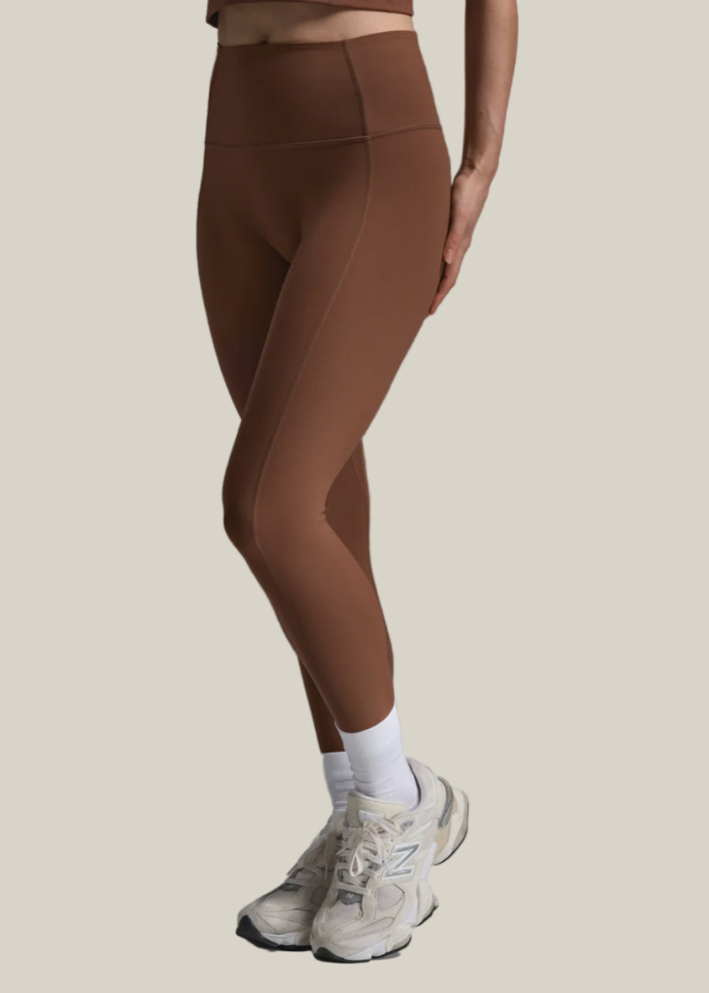 Brown leggings worn by a person on a gray background