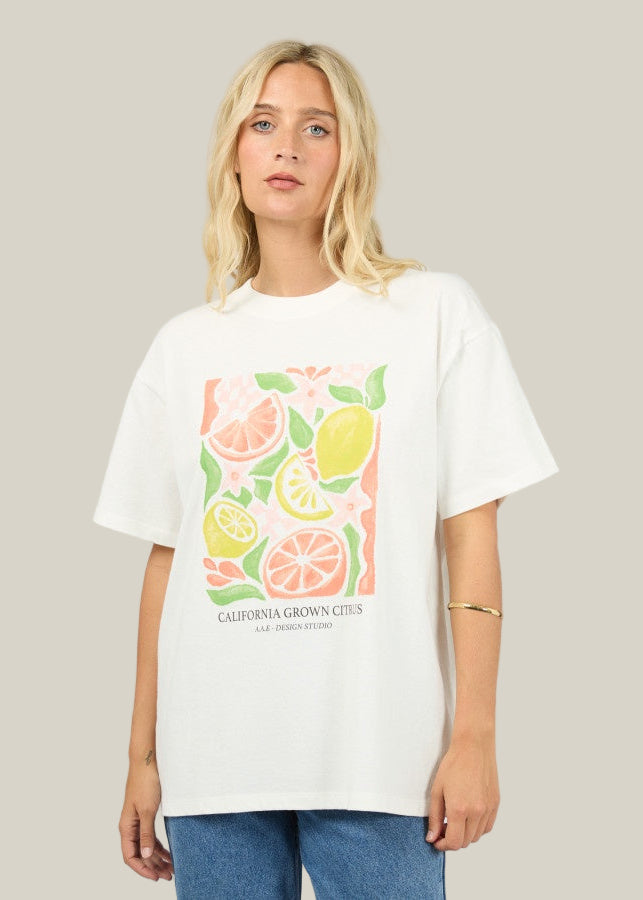 Person wearing a white t-shirt with fruit graphic and text on a plain background